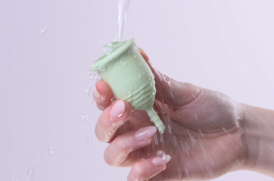 Green period cup splashed with water.