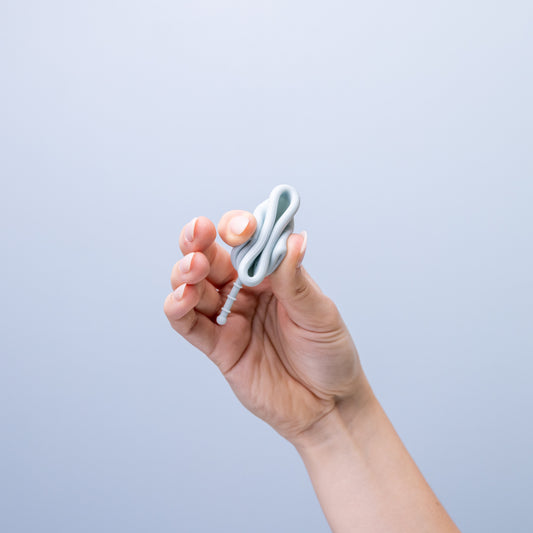 Image of hand squeezing tightly on bblue period cup folded into a long shape against a blue background.