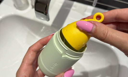 Person putting a yellow period cup into a green cleaning case. 